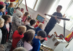 Pan Sławek prezentuje dzieciom zabytkową sikawkę.
