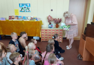 Pani Ula demonstruje dzieciom książkę o gąsienicy, która zmieniła się w motyla.