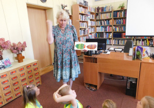 Pani Ula demonstruje dzieciom książkę pt. "Bardzo głodna gąsienica".