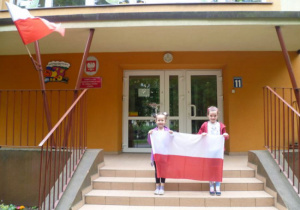 Dzieci przed wejściem przedszkola z flagą 