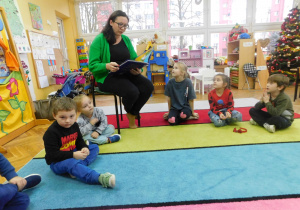 Mama Karinki, pani Karolina Szymczak czyta dzieciom książkę.