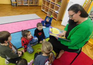 Dzieci z grupy Słoneczek uważnie słuchają opowieści czytanej przez panią Karolinę.