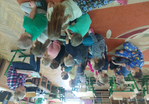 Dzieci siedzą na dywanie i słuchają czytanej bajki.