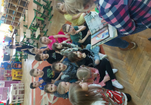 Dziewczynki i chłopcy słuchają czytanej bajki.