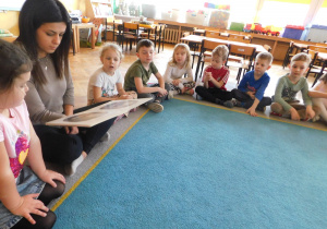 Dzieci w skupieniu słuchają na dywanie bajki czytanej przez panią Anetkę.