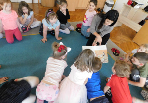 Dzieci oglądają ilustrację w książce, które pokazuje pani Anetka.