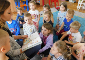Dzieci w skupieniu słuchają bajki czytanej przez panią Aleksandrę Grzelak.