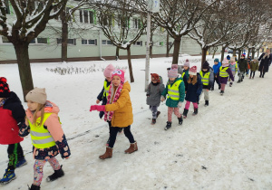 Dzieci w parach spacerują po śniegu.