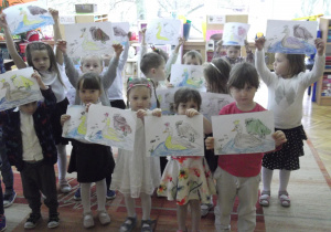 Dzieci pokazują pokolorowaną malowankę.