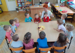 Dzieci przy wspólnym stole przyglądają się szczypiorkowi.