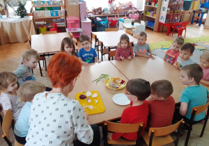 Dzieci przyglądają się jak pani Agnieszka kroi cebulę na syrop.