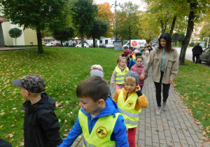 Mama Lenki towarzyszy dzieciom z grupy Biedronek podczas spaceru alejkami miasta.