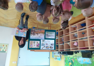 Pani Anetka pokazuje dzieciom ilustracje świnki Peppy w książce.