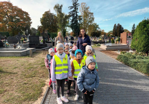 Mamusia Nikodema i Karinki towarzyszą dzieciom w spacerze na cmentarz.