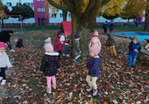 Dzieci ścigają się wokół drzewa.