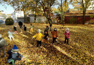 Dzieci radośnie bawią się na barwnym dywanie z liści.