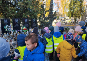 Dzieci stoją przed pomnikami.