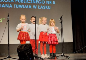 Dzieci stoją na scenie i śpiewają piosenkę.