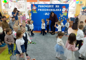 Dzieci maszerują parami w rytm piosenki.