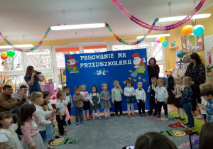 Dzieci w półkolu śpiewają piosenkę.