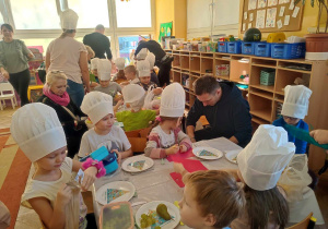 Dzieci wyjmują owoce i warzywa na talerzyki.