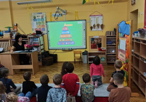 Przedszkolaki oglądają piramidę żywieniową na tablicy interaktywnej.