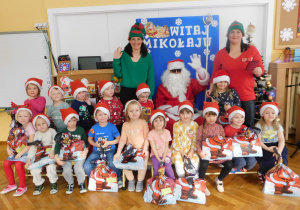 Grupa "Misiaczków" pozuje do zdjęcia z Mikołajem i elfami.