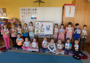 Dzieci z grupy "Biedronek" stoją i trzymają obrazki.