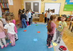 Dzieci szukają kwiatka w odpowiednim kolorze w zabawie muzyczno-ruchowej.