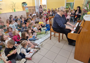 Przedszkolaki uważnie słuchają wesołego utworu granego przez Panią Walerię na pianinie aby nie przegapić momentu wyklaskiwania rytmu.
