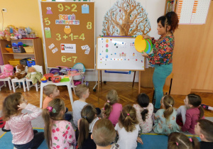 Pani Kamilka objasnia dzieciom zasady zabawy "Zakodowane kolorowe jajka".