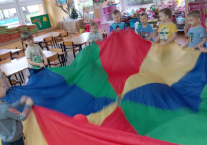 Dzieci ruszają chustą, na której leży balon.