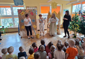 Królowa Czystella i Kocmołuszek przyglądają się jak sprzątają dzieci, w których rolę wcieliły się pani Agnieszka i pani Renia.