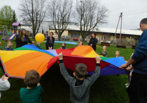 Zabawa z chustą „ Trampolina”- dzieci i rodzice podrzucają piłkę tak aby nie spadła.