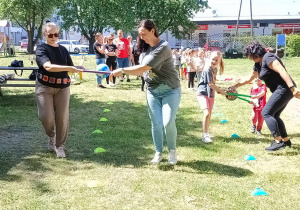 Rodzice i dzieci przenoszą „rannego” czyli piłkę na dwóch laskach.