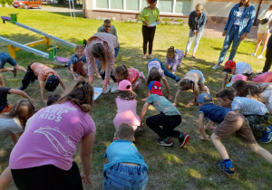 Dzieci i rodzice naśladują rybkę w zabawie ruchowej.