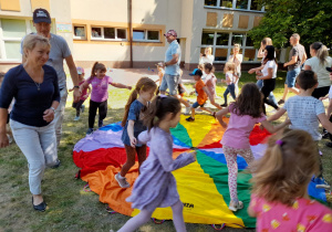 Rodzice i dzieci podczas zabawy z chustą animacyjną "Sałatka owocowa".