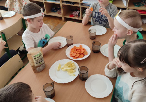 Dzieci jedzą ekologiczną marchewkę i jabłko.