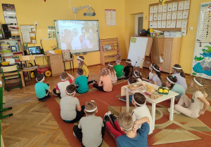Dzieci oglądają film edukacyjny na tablicy interaktywnej.