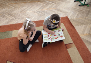 Kaja i Oliwier oglądają książkę z produktami ekologicznymi.