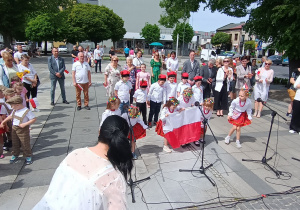 Gabrysia, Kaja i Julia trzymają flagę Polski.