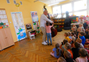 Julek z pomocą pana Feliksa gra na instrumencie.