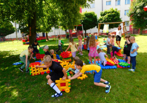 Przedszkolaki bawią się duzymi klockami.