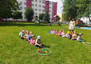 Misiaczki siedzą w dwóch rzędach przed nimi leżą kolorowe piłki.