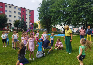 Starszaczki przewlekają obręcz przez dzieci .