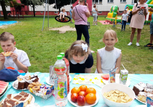 Amelka, Zosia i Dawid siedzą przy stole.