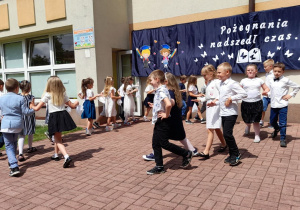 Starszaki tańczą parami w kole.