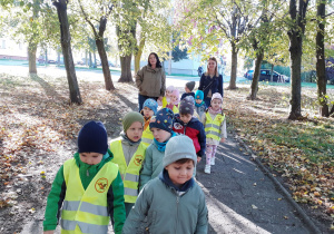 Krasnoludki idą osiedlową alejką, na końcu idzie pani Daria i pani Ania.