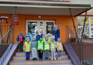 Dzieci wraz z gościem stoją na schodach przed przedszkolem.