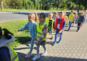 Dzieci z grupy "Biedronek" idą żwawo chodnikiem.